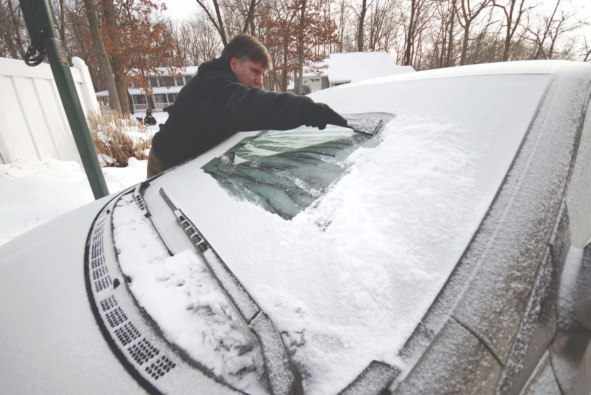 Man scraping snow of windscreen