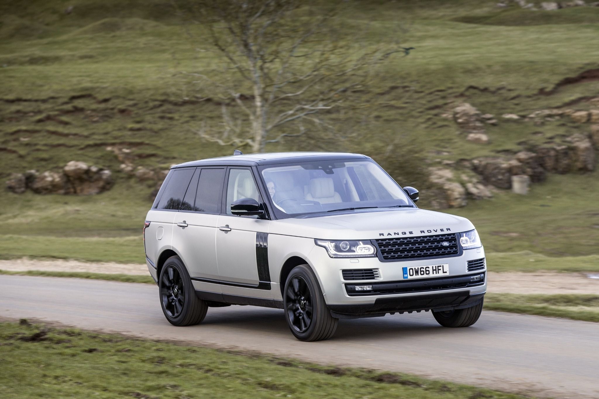 Range Rover driving down a road next to grass