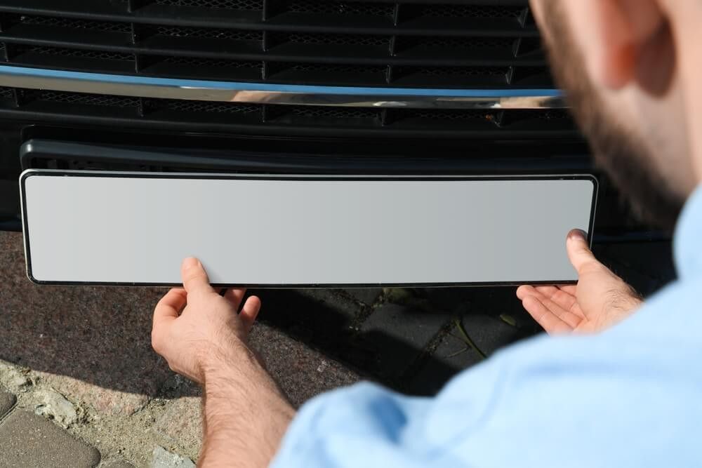 Man holding a blank registration plate