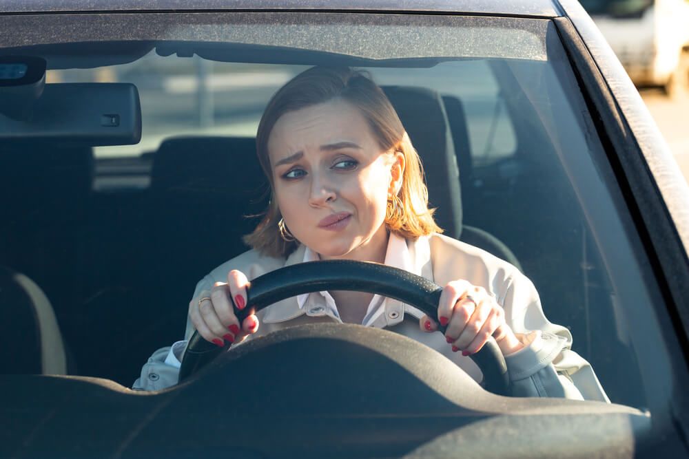 Woman looking confused behind a steering wheel